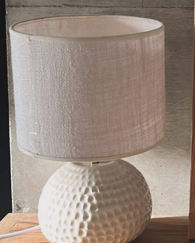 Lámpara de base esférica en cerámica blanca con textura de hoyuelos y pantalla de lino crudo