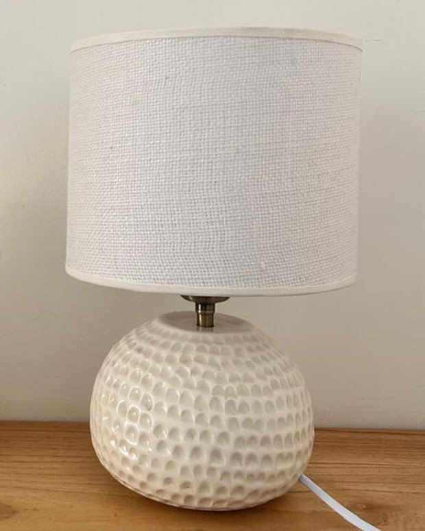 Lámpara de base esférica en cerámica blanca con textura de hoyuelos y pantalla de lino crudo